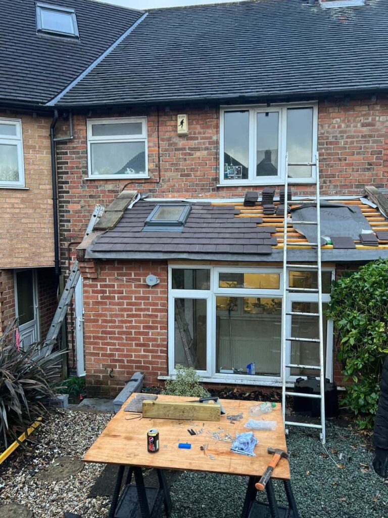 This is a photo of a roof extension that is having new roof tiles installed. This is a photo taken from the roof ridge looking down a tiled pitched roof on to a flat roof. Works carried out by Bingham Roofing Repairs